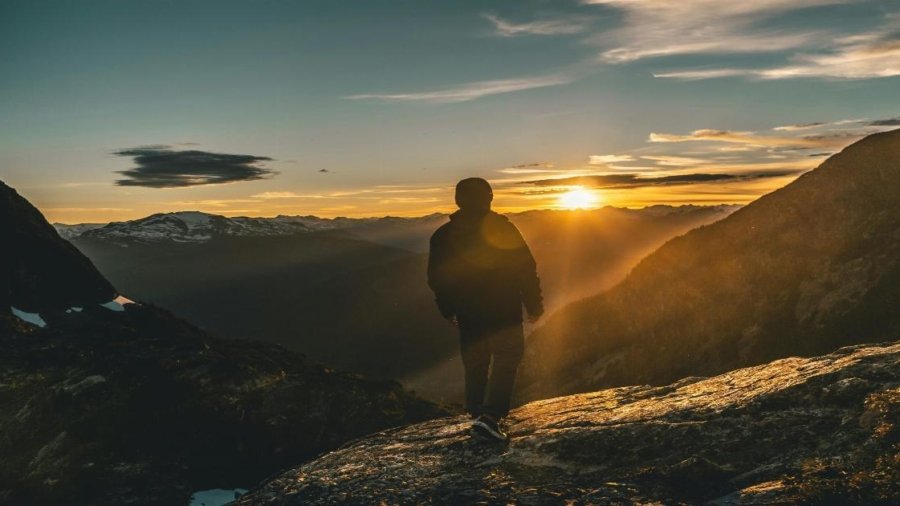 A person standing on a mountain peak at sunrise