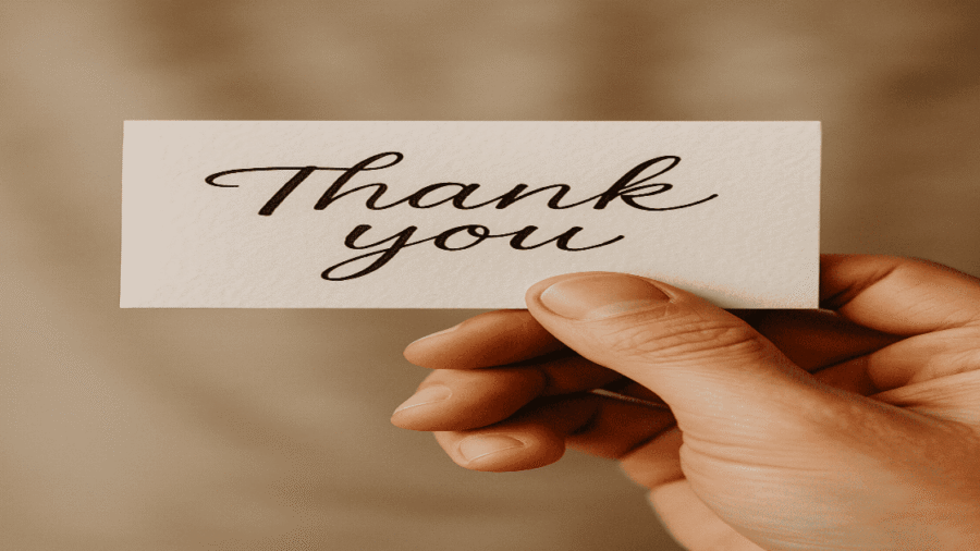 A close-up of a hand holding a 'thank you' note