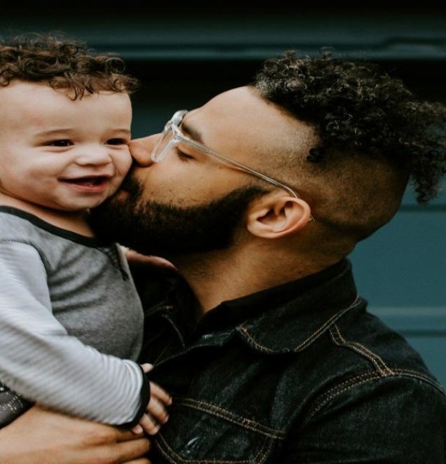 man carrying baby boy and kissing on cheek