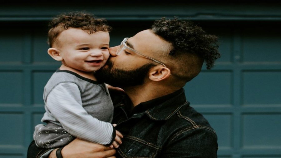 man carrying baby boy and kissing on cheek