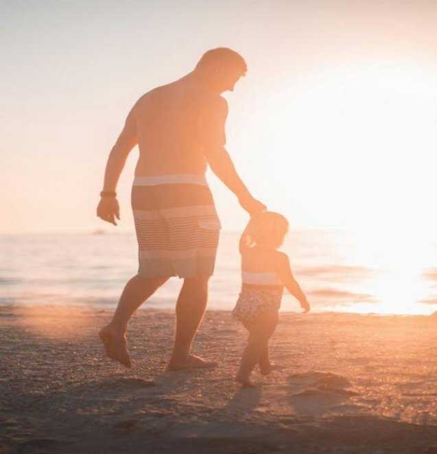 man holding girl heading towards sea
