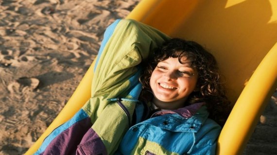 A young boy laying in a beach chair on the sand