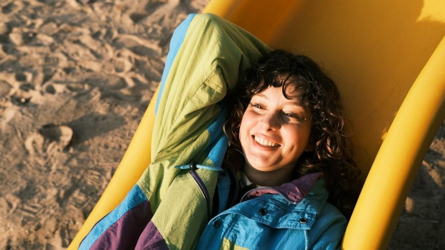 A young boy laying in a beach chair on the sand