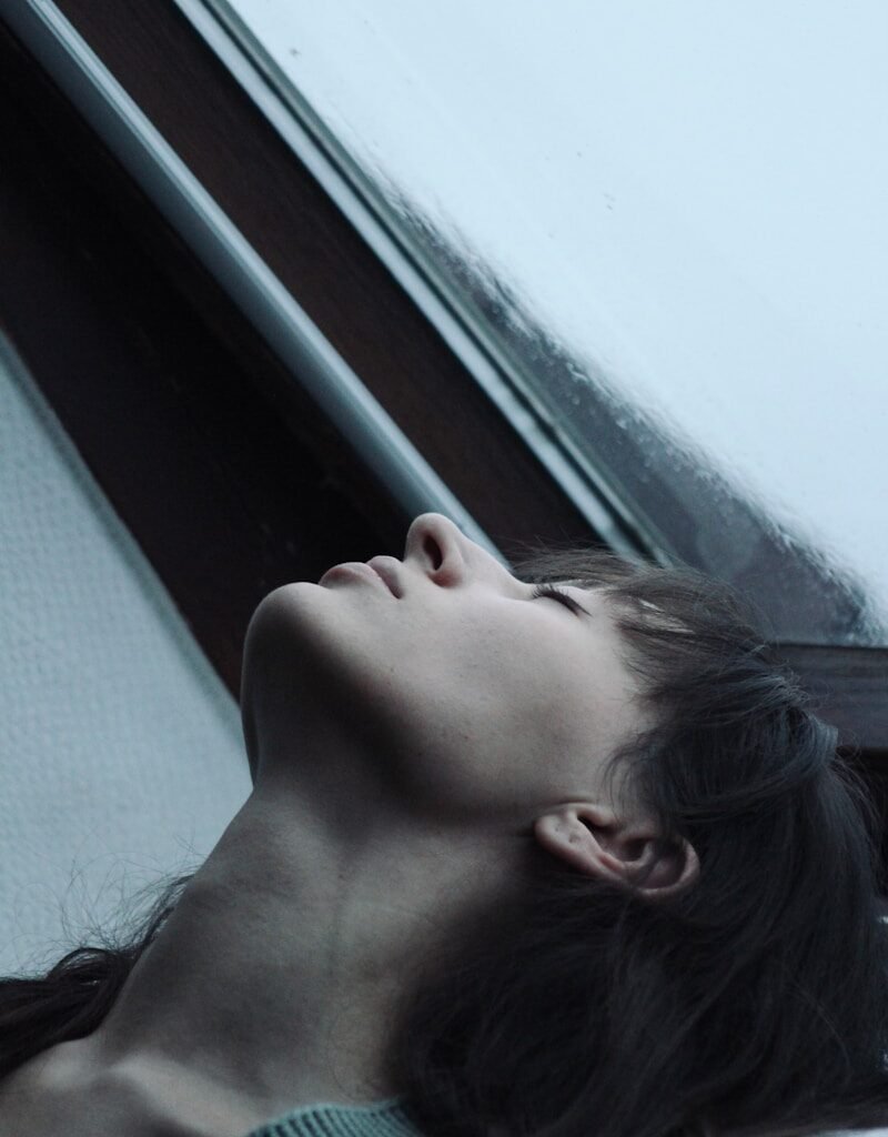 person practicing 5-minute self-care breathing exercise near window
