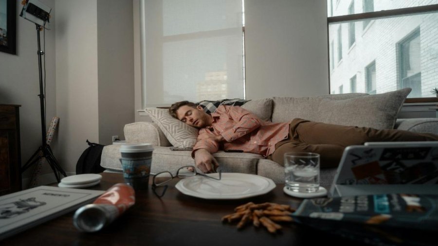 a woman laying on a couch with a plate of food