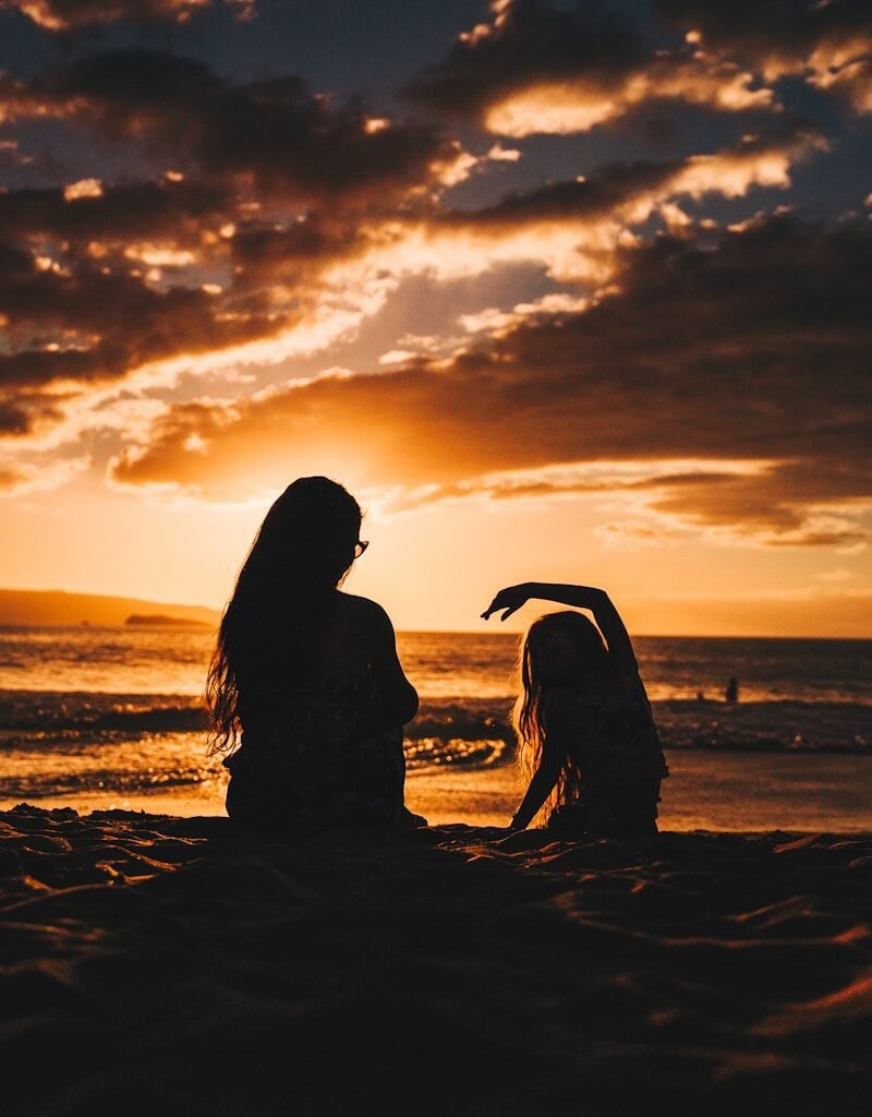 silhouette photo of woman and girl on shoreline signifying a secure attachment relationship between child and caregiver